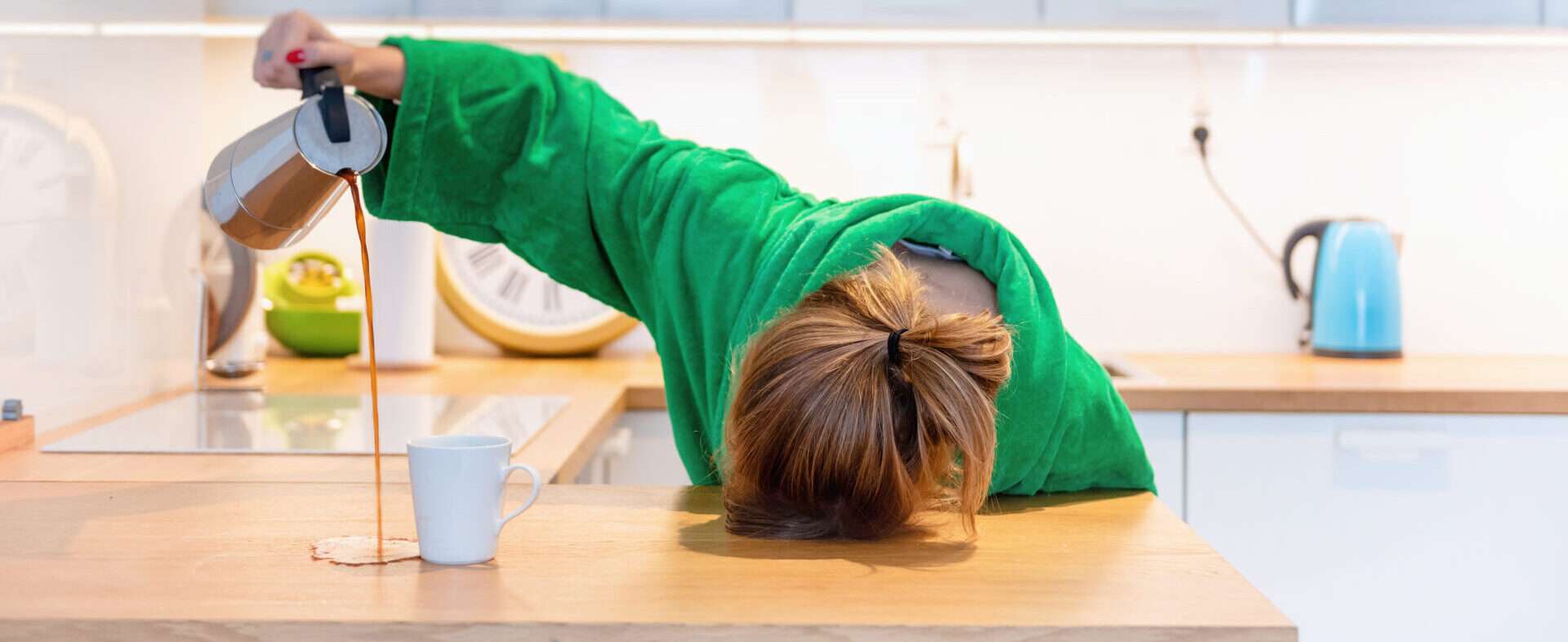 緑色のローブを着た女性がキッチンカウンターの上に立っています。彼女はまるで以前にも同じことをしたことがあるかのように、安心した表情をしています。