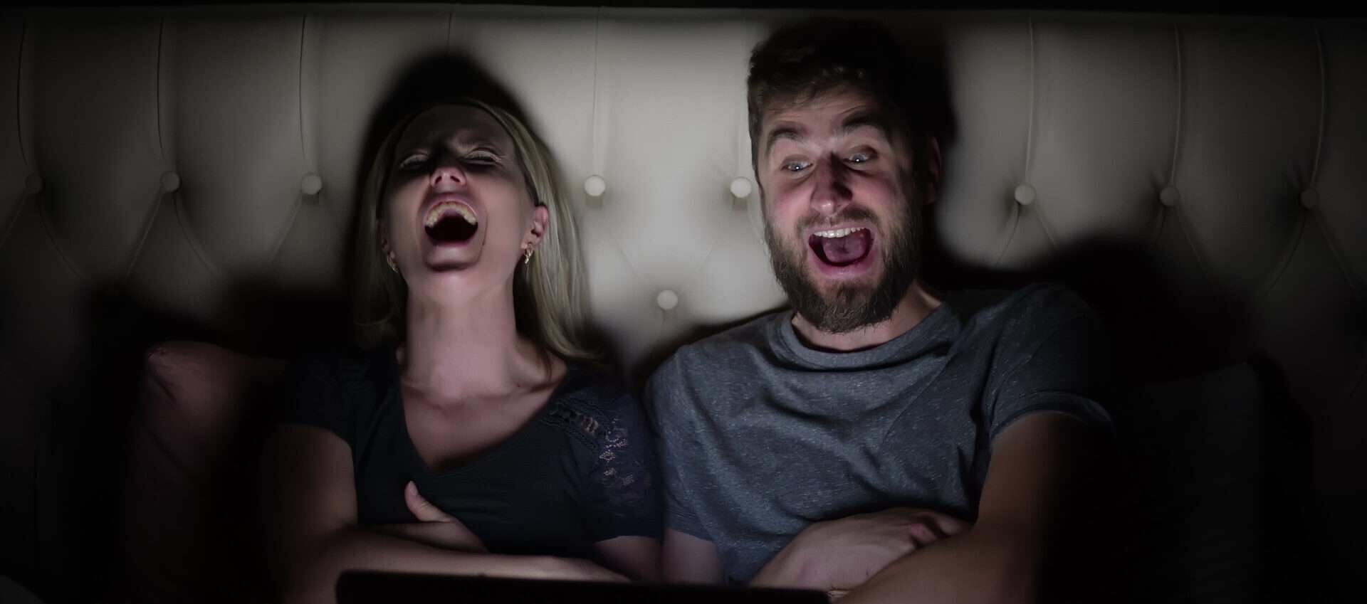 暗い部屋で男女が笑い合っている。