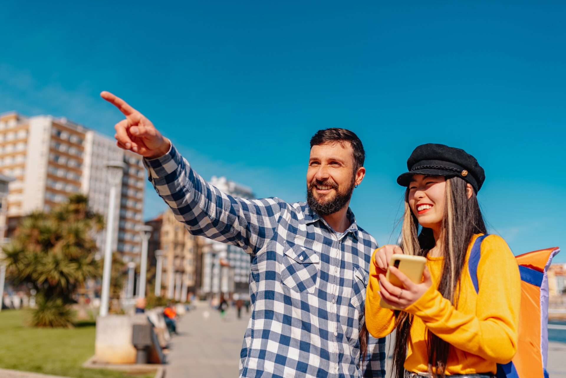 街を歩きながら携帯電話で何かを指している若いカップル。英語で話し合うカップルは生き生きとした表情を浮かべている。