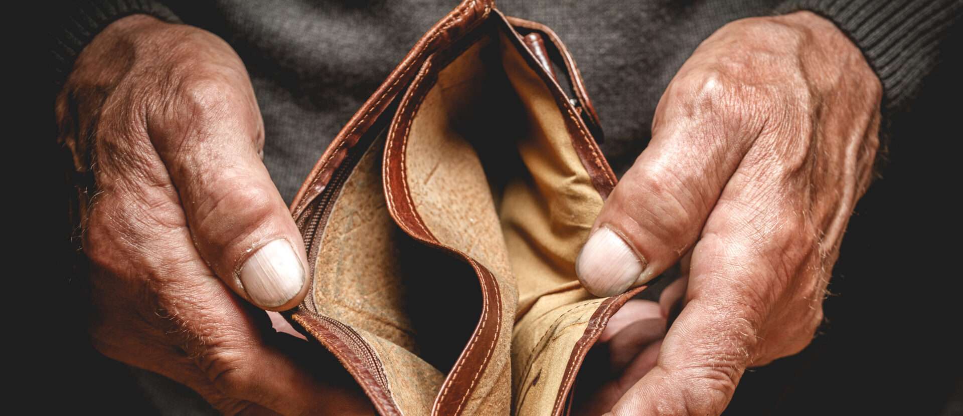 空の財布を握り締める老人の手。