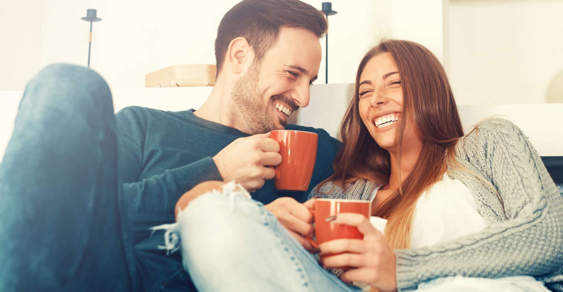 コーヒーマグを持ってソファに座っている男性と女性。