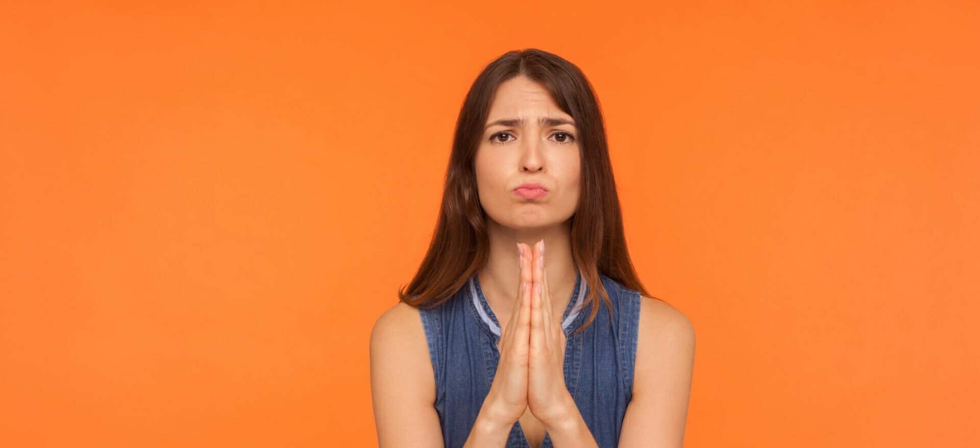 オレンジ色の背景に祈る若い女性、日本語。