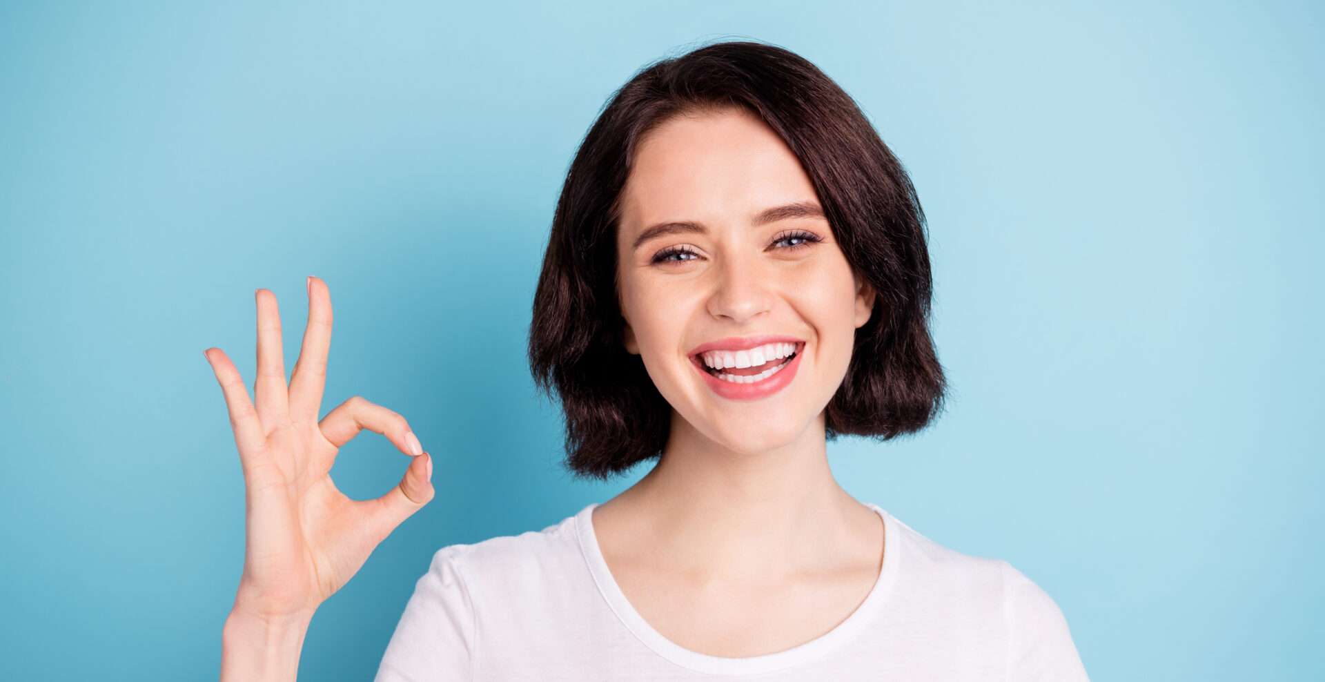 青色の背景に OK サインを出す若い女性。 青色の背景に OK サインを出す若い女性。
