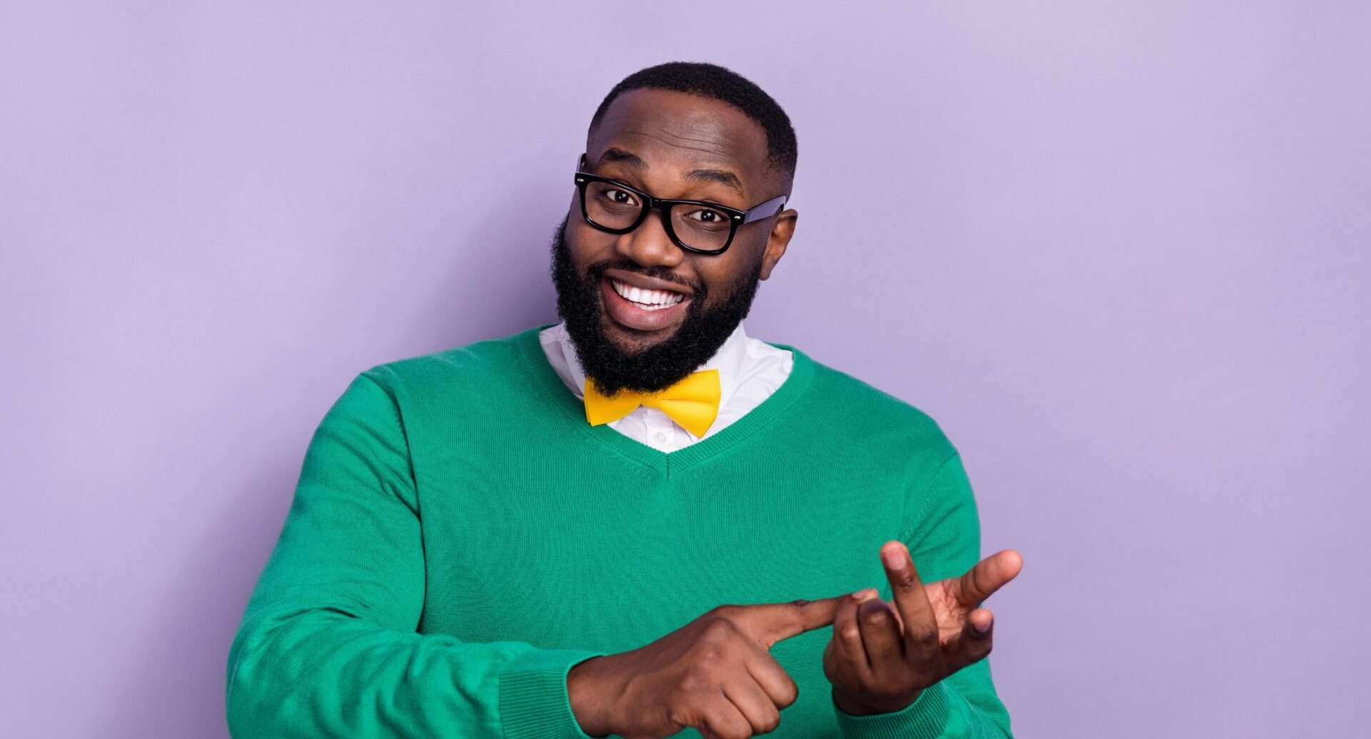 メガネをかけ、緑のセーターを着た黒人男性が指をさしている。