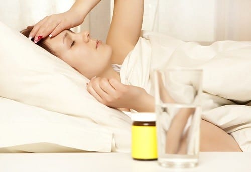 水の入ったボトルを頭に乗せてベッドに横たわって英会話の練習をする女性。