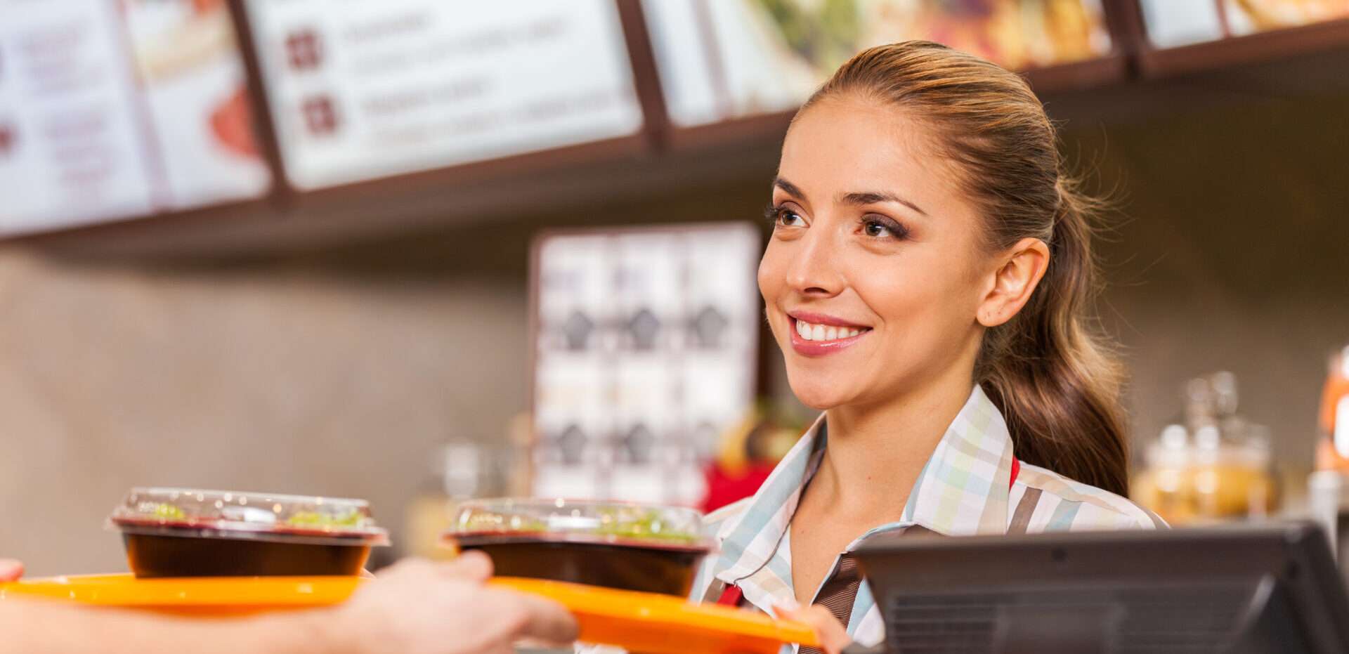 ファーストフード店で客に料理を提供する女性。 ファーストフード店で客に料理を提供する女性。