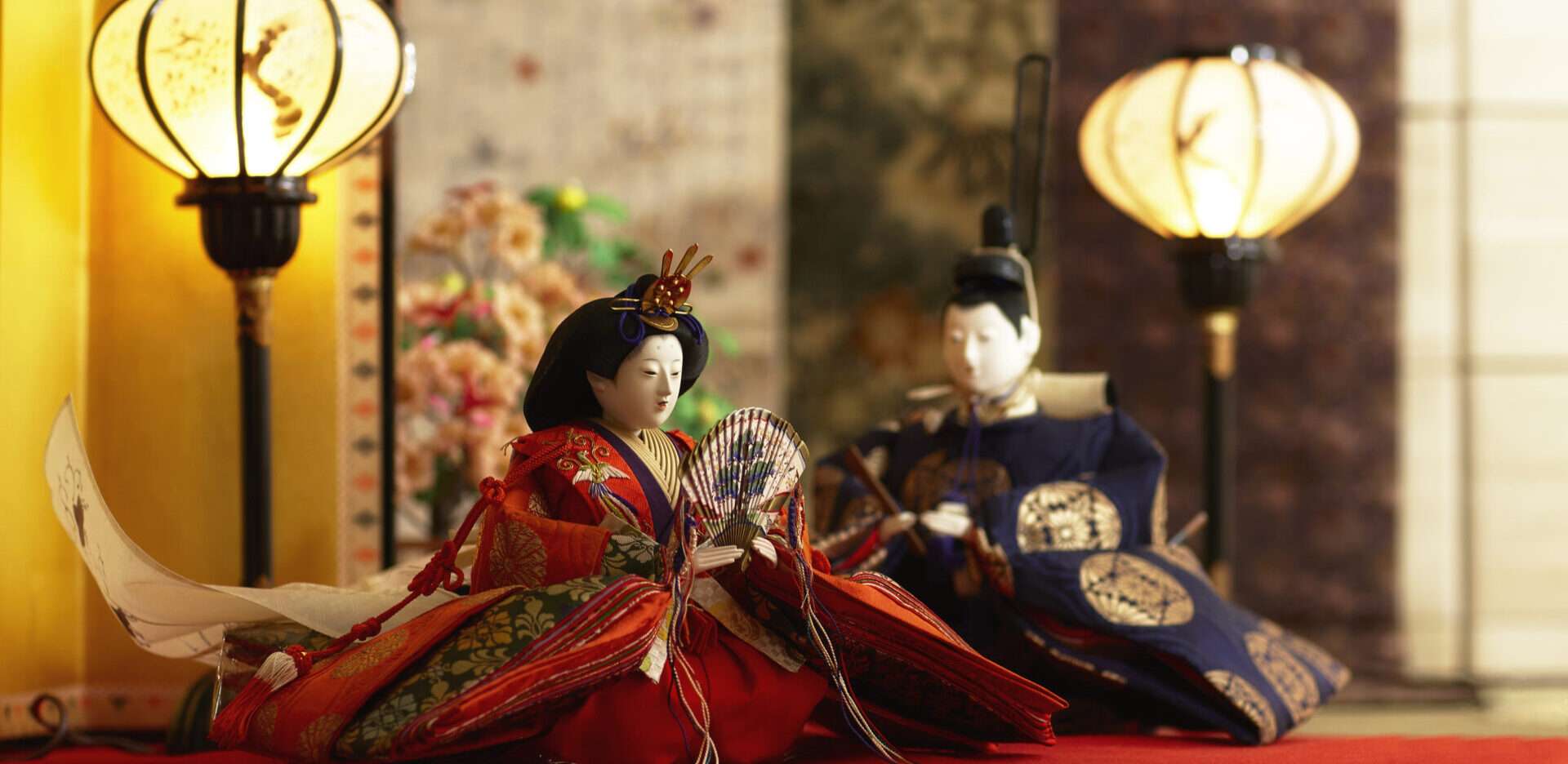 赤い敷物の上に座っている 2 つのアジアの人形。