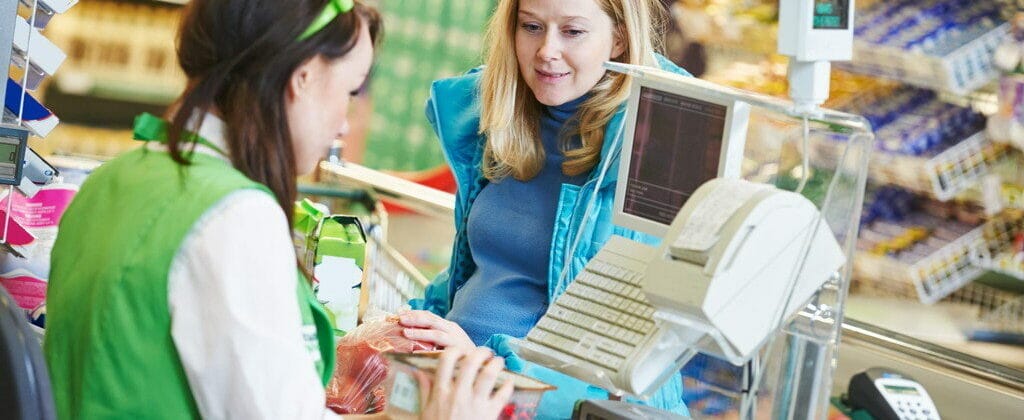 食料品店のレジカウンターで、英語で英会話をする 2 人の女性。
