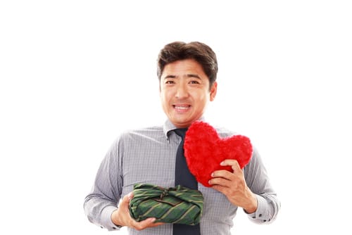 赤いハート型のテディベアを抱えて英会話の練習をしている男性。