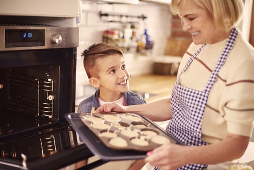 英会話をしながらオーブンでクッキーを焼く女性と少年。
