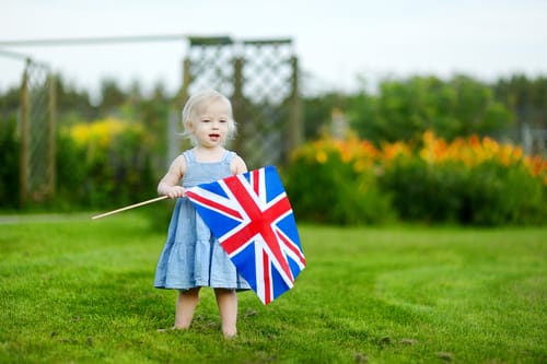 草の中でイギリス国旗を掲げ、イギリスへの愛と英語への愛を示す少女。