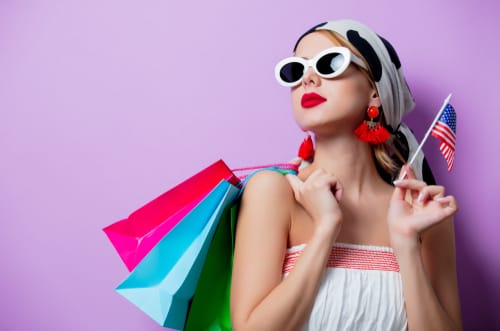 サングラスとアメリカ国旗を持ったショッピングバッグを持った女性が、活発な英会話セッション中にアメリカへの愛を熱心にアピールしています。