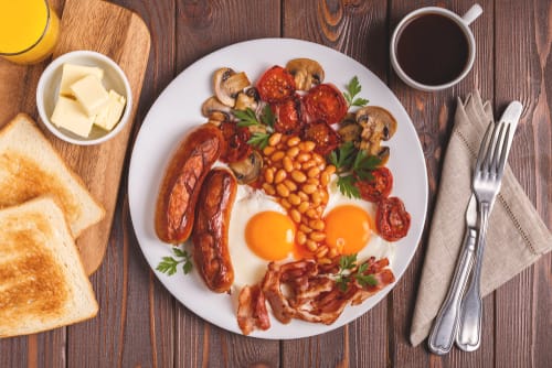 木のテーブルに朝食用の食べ物が盛られたプレート。英会話や英会話の練習に最適です。