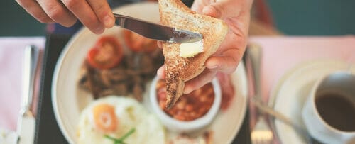 日本語の朝食中に食べ物の皿の上でトーストを切る人。