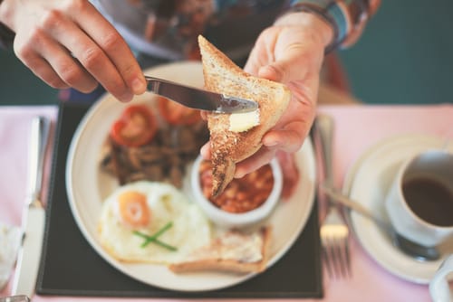 日本語の朝食中に食べ物の皿の上でトーストを切る人。