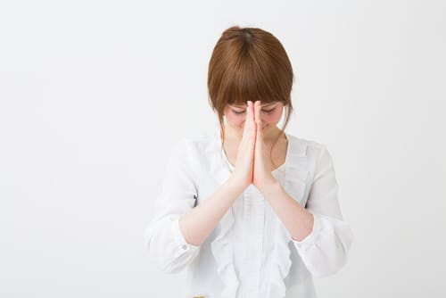 白い背景に英会話の練習をしながら静かに祈る若い日本人女性。