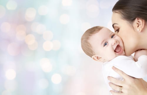 英会話の授業中、ボケ味の背景の前で赤ちゃんにキスする女性。