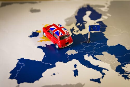 ヨーロッパの地図の上におもちゃの車が置かれ、周りには英語の教材や会話ガイドが散らばっています。 ヨーロッパの地図の上におもちゃの車が置かれ、周りには英語の教材や会話ガイドが散らばっています。