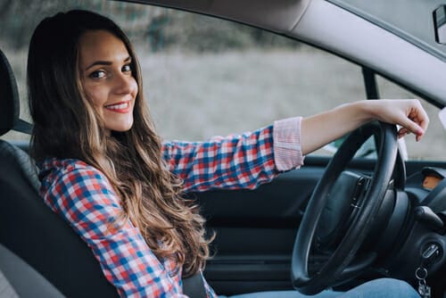 車の運転席に座って英会話に興じる若い女性。