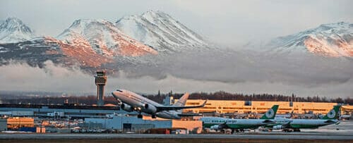 雪山を背景に空港で飛行機が離陸します。