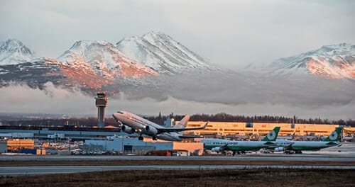 雪山を背景に空港で飛行機が離陸します。