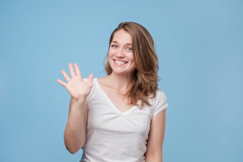 青い背景に、英会話中に身振り手振りをする若い女性。 青い背景に、英会話中に身振り手振りをする若い女性。