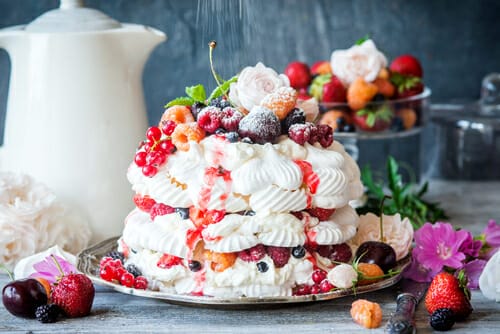 プレートにベリーと花が描かれたメレンゲ ケーキ。アフタヌーン ティーのお祝いに最適です。