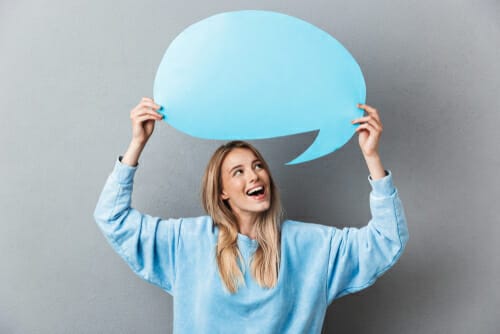 青い吹き出しを掲げて英会話をする若い女性。 青い吹き出しを掲げて英会話をする若い女性。