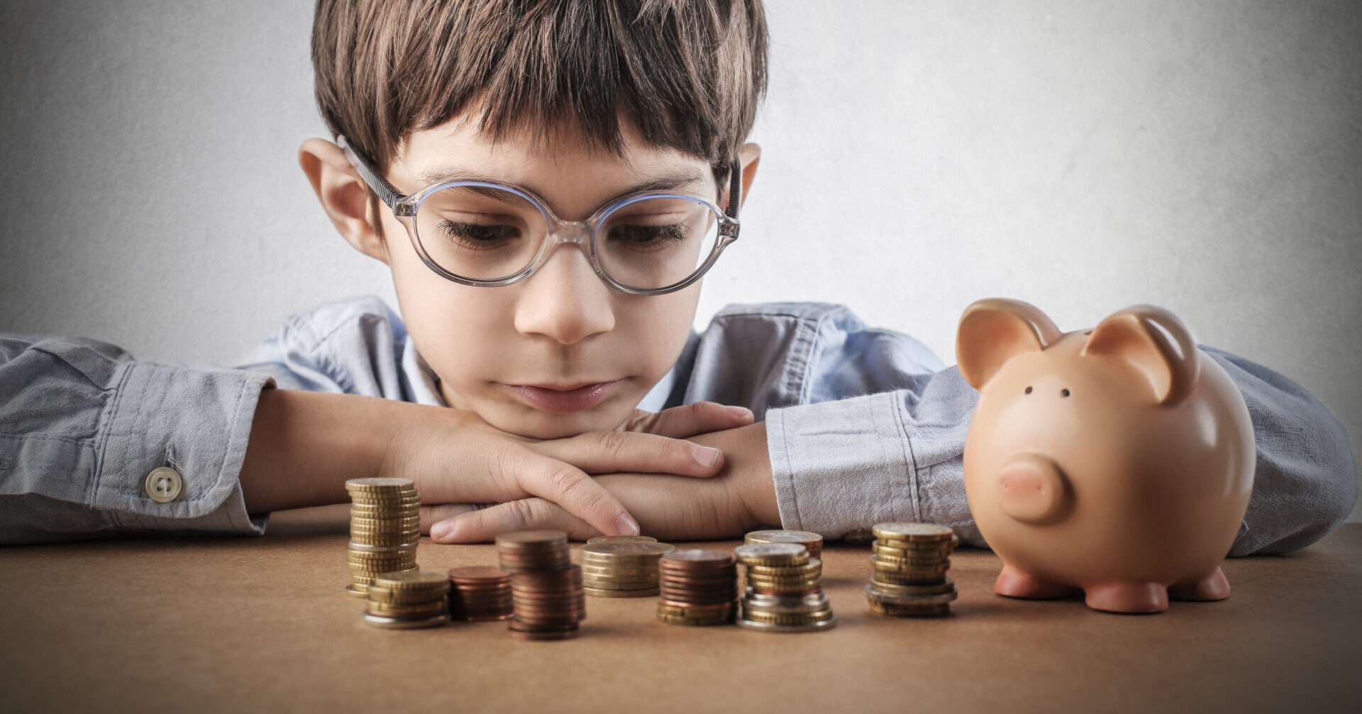 英語で貯金箱の隣に座っているメガネの少年。