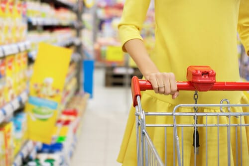 女性がスーパーマーケットでショッピングカートを押しています。