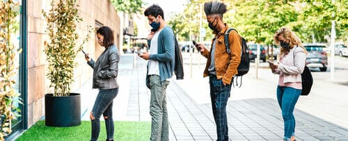 歩道に立って携帯電話に夢中になっている人々のグループ。