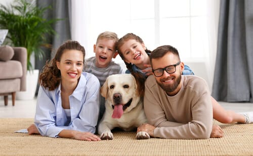 床でくつろぐ犬を連れた家族。