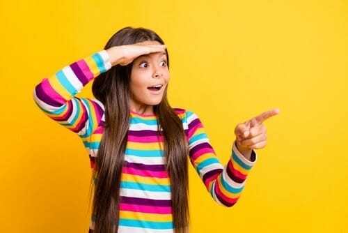 カラフルなシャツを着た女の子が何かを指しています。