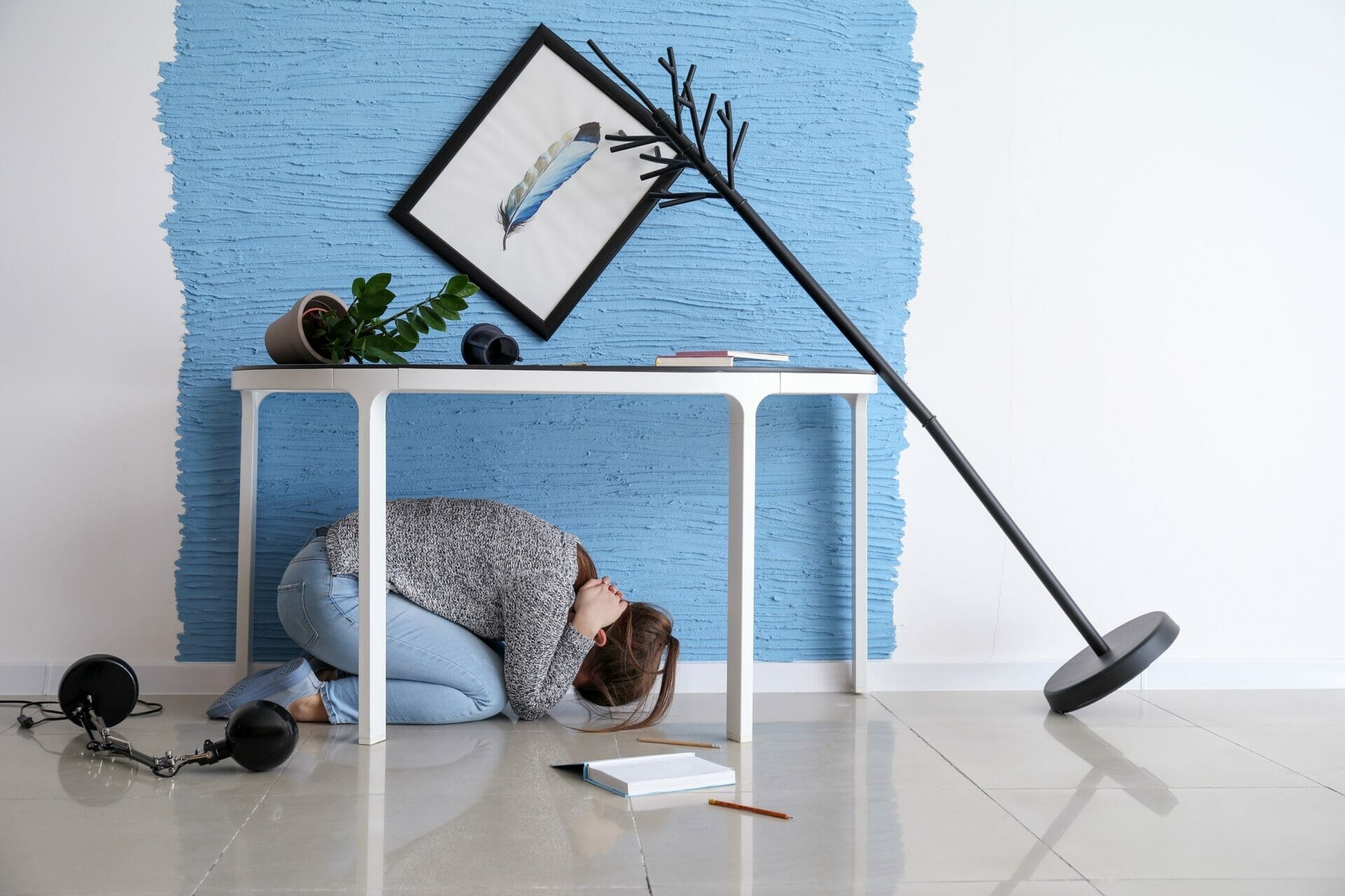 女性が青い壁の前にひざまずいている。 (英語)