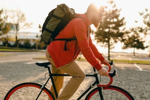 バックパックを背負って自転車に乗る男性。 （英語）