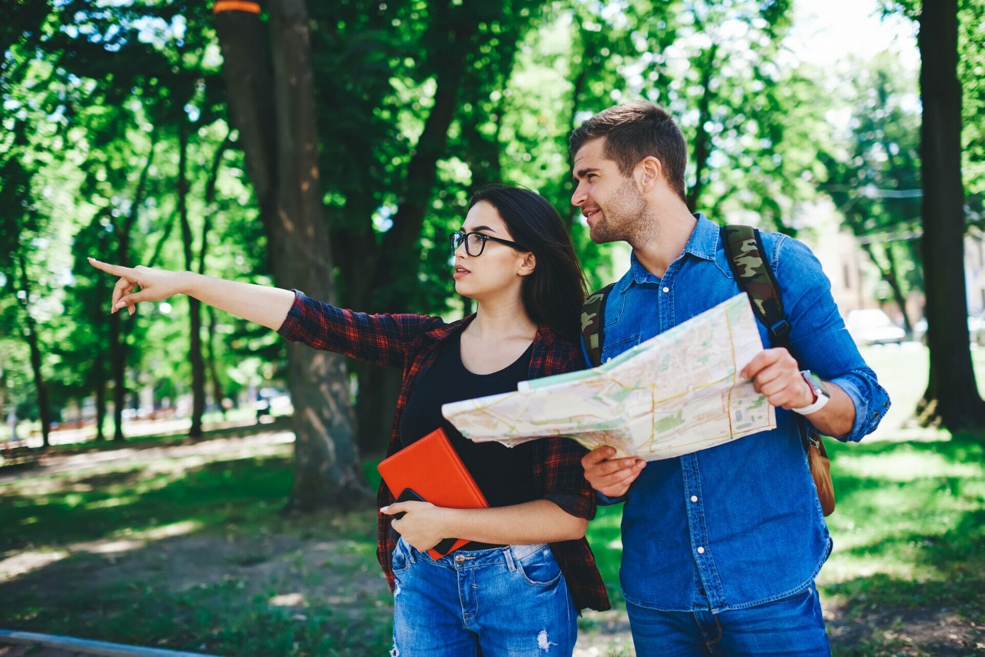公園で地図を勉強している若いカップル。