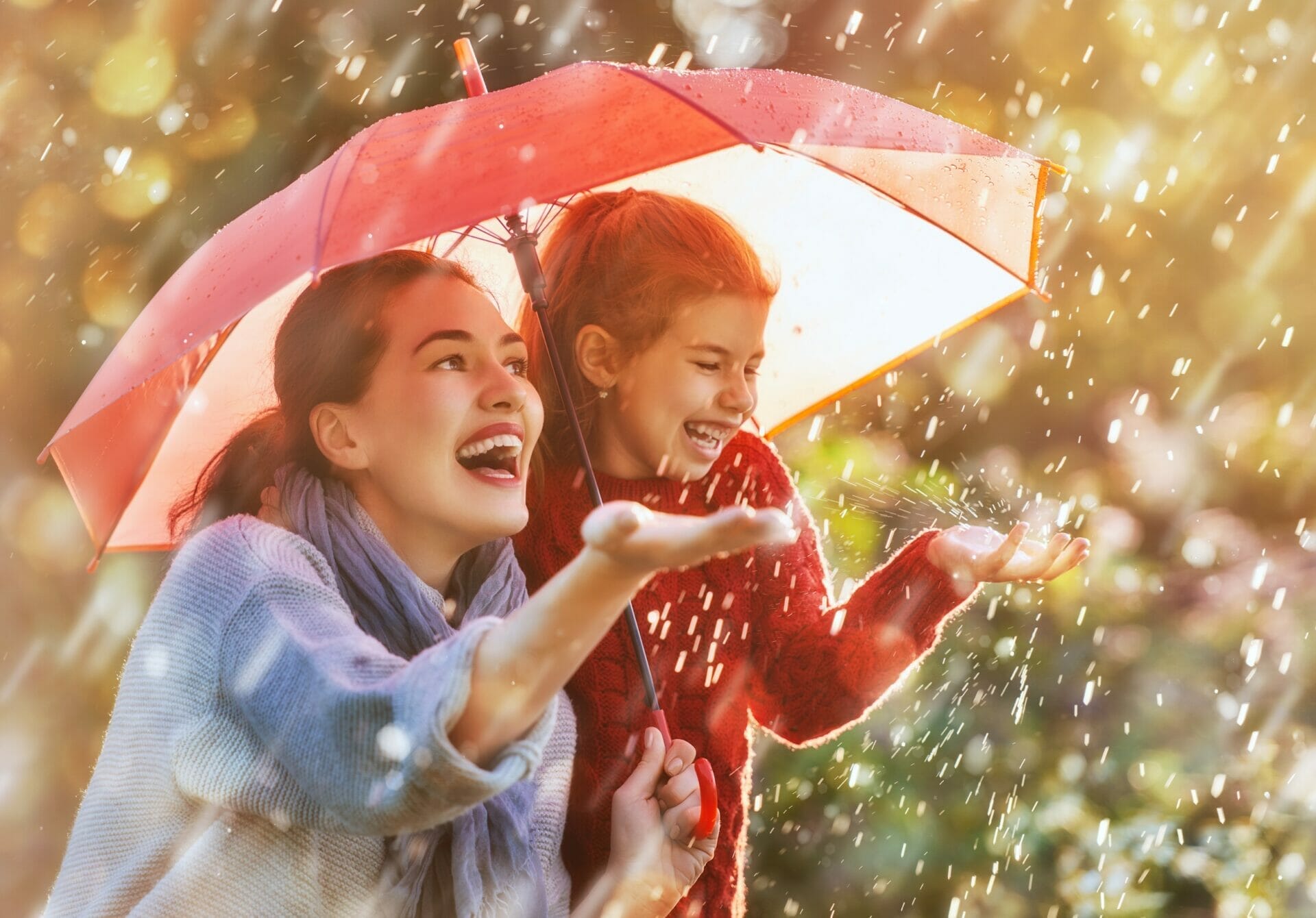 雨の中、傘の下に立つ母と娘。