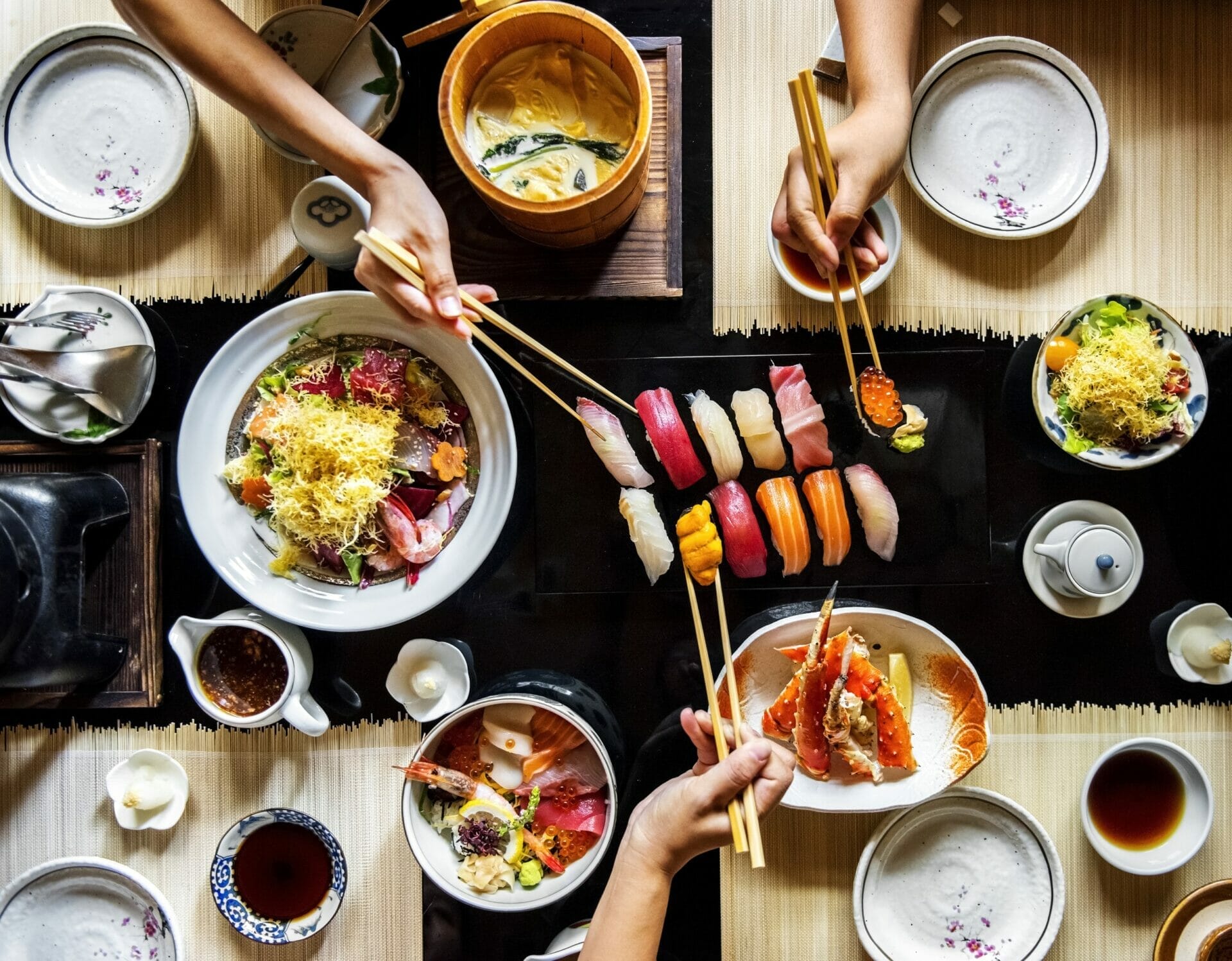 テーブルで日本料理を楽しむ人々のグループ。 テーブルで日本料理を楽しむ人々のグループ。