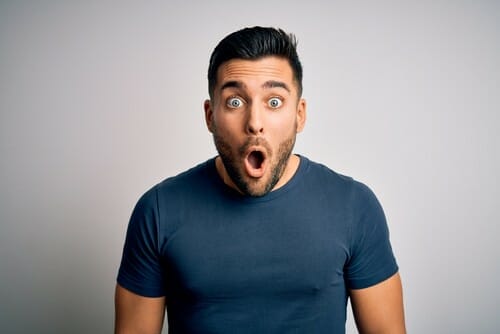 灰色の背景に驚いた顔をした男性が驚いているように見えます。