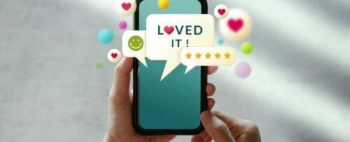 英語で「loved it」と書かれたスマートフォンを掲げる女性。