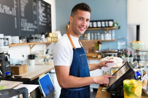 英国風の喫茶店のカウンターに立つエプロン姿の男性。