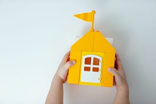 白い背景に黄色のおもちゃの家を持つ子供。 （日本語）