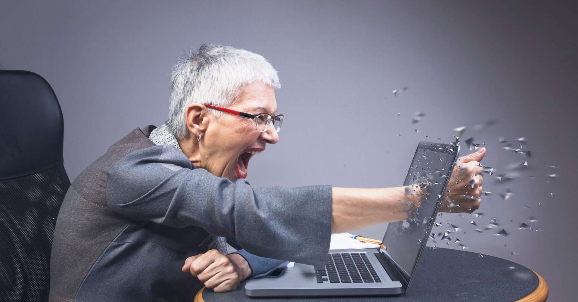 英語の Web サイトにアクセスしようとしているときに、ラップトップを激しく叱る年配の女性。