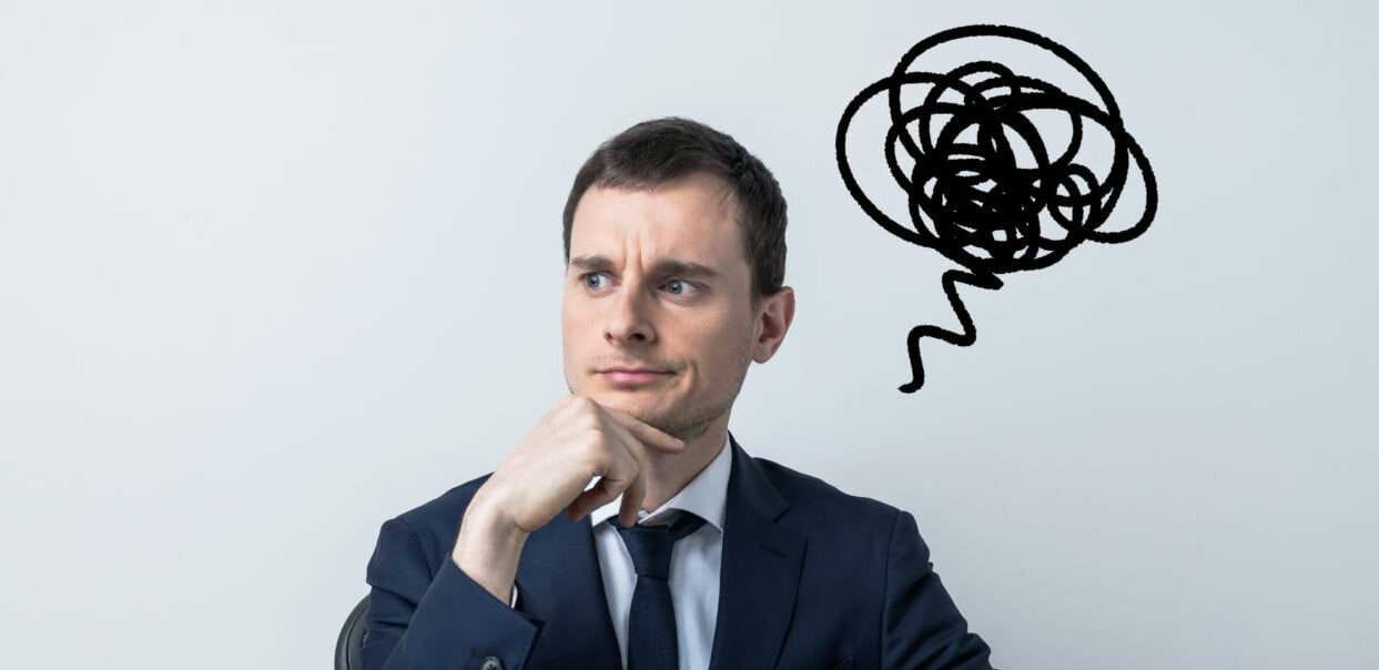 スーツを着た男性が頭の上に吹き出しを浮かべて考えている。