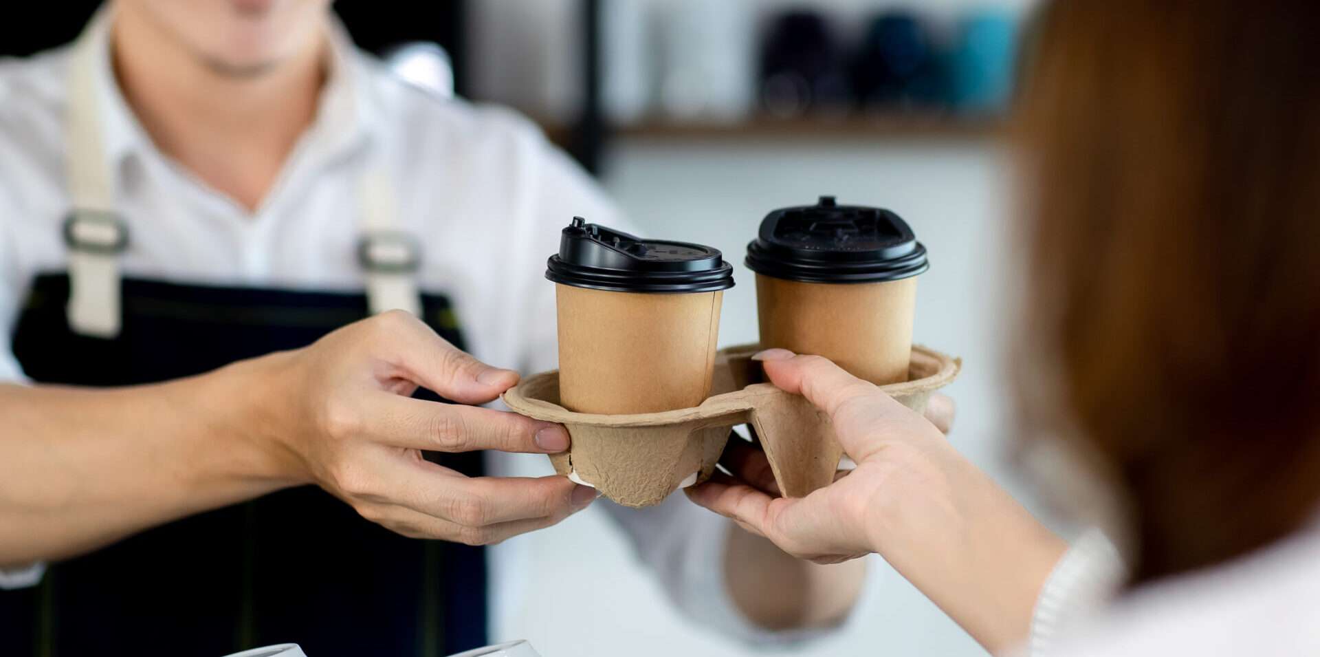 女性がお客様にコーヒーを提供しています。