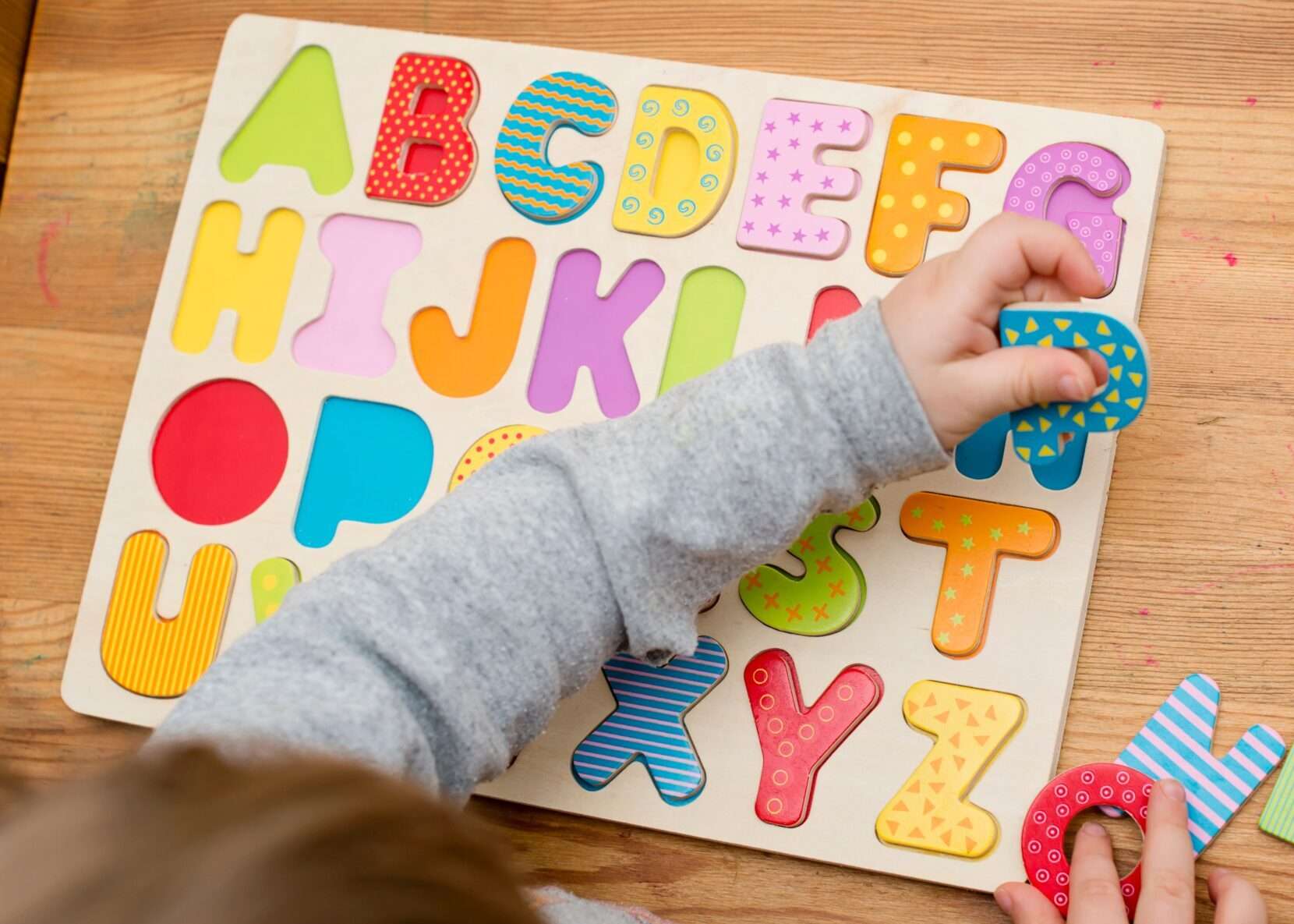 子供が英語のアルファベットのパズルで遊んでいます。