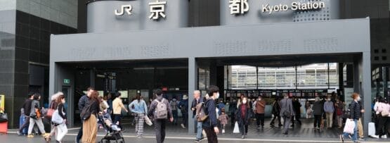 「JR」と「京都駅」の看板が掲げられた京都駅の入り口前は人々が行き交い、英会話マンツーマンの交流や、活気に満ちた街並みに浸るのに最適な賑やかな雰囲気を作り出しています。.