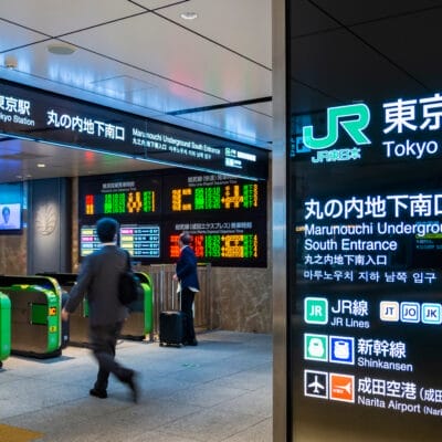 東京駅丸の内地下南口の改札付近を歩いている人々は、電飾看板やデジタルディスプレイに囲まれ、旅行者が移動中に英語を練習する際の英会話マンツーマンのレッスンの断片を耳にすることがあります。.