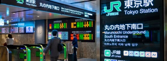 東京駅丸の内地下南口の改札付近を歩いている人々は、電飾看板やデジタルディスプレイに囲まれ、旅行者が移動中に英語を練習する際の英会話マンツーマンのレッスンの断片を耳にすることがあります。.