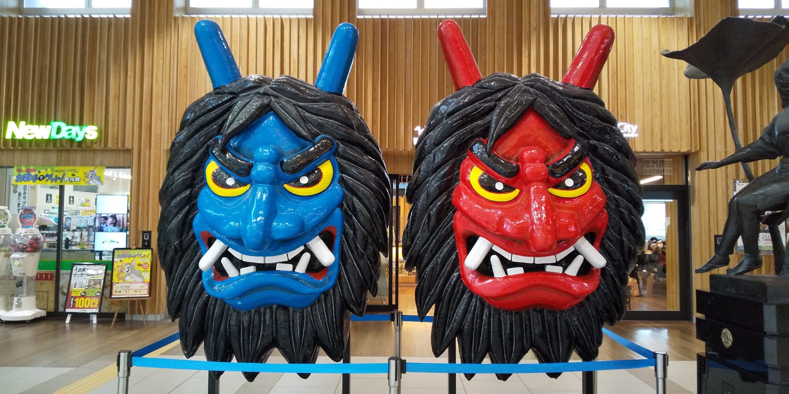 店内には秋田の伝統を彷彿とさせる木造の内装と、背後に店舗を配し、青と赤の大きな鬼の面が凶暴な表情で飾られている。.